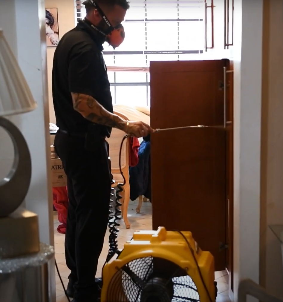 Worker using pest control spray in a closet, part of Pest Control Service in Cicero to protect against hidden pests.